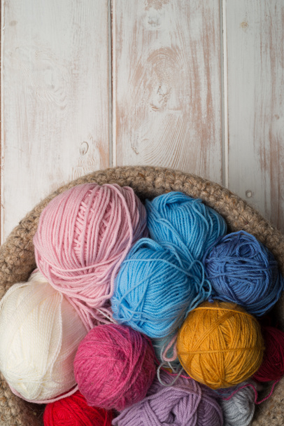 Bolas de lana de color en cuenco sobre fondo de madera
 - Foto, imagen