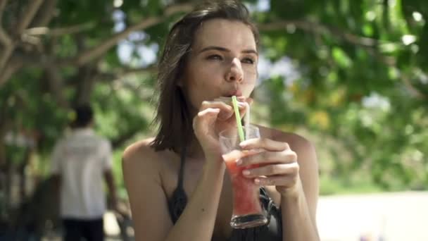 woman drinking tropical cocktail in park - Video