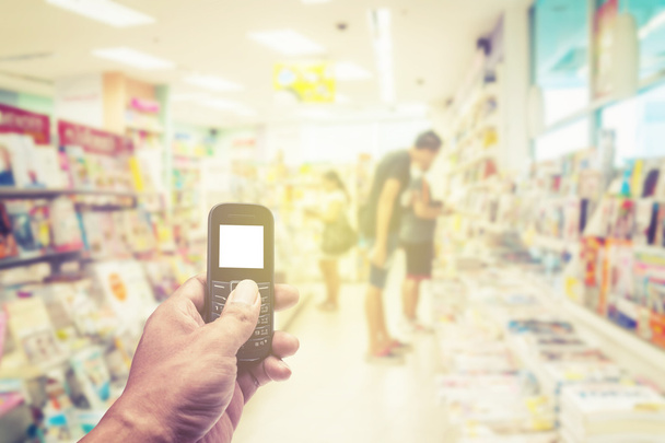 Телефон білий екран в руці на розмитому книжковому магазині
 - Фото, зображення
