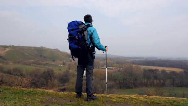 Man tourist in a blue jacket with a backpack enjoys his climbing - Felvétel, videó