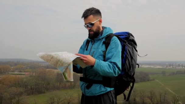 Man tourist in a blue jacket with a backpack looking on the map - Filmagem, Vídeo