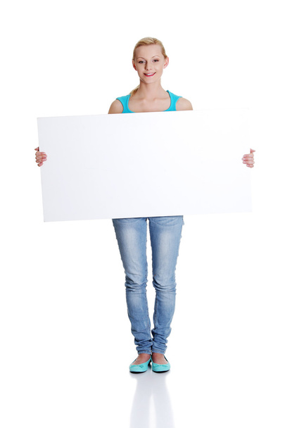 Beautiful young woman is holding blank whiteboard sign - Φωτογραφία, εικόνα