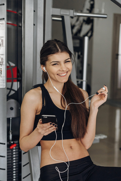 Beautiful girl with a phone in the gym - Фото, изображение