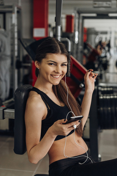 Beautiful girl with a phone in the gym - Fotografie, Obrázek