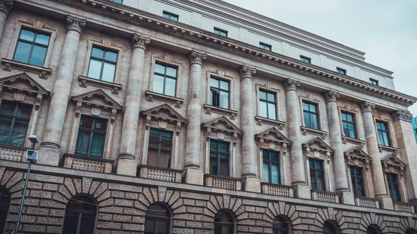 Nízkoúhlý architektonický pohled na historické budovy s klasickými pilíři a dekorativními prvky v městském prostředí v den zatažení v Berlíně, Německo - Fotografie, Obrázek