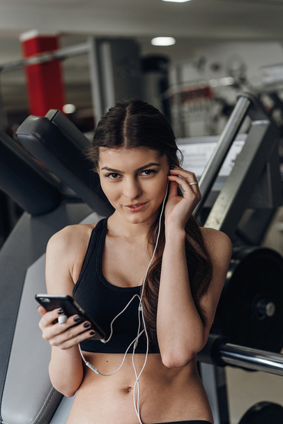Beautiful girl with a phone in the gym - Zdjęcie, obraz