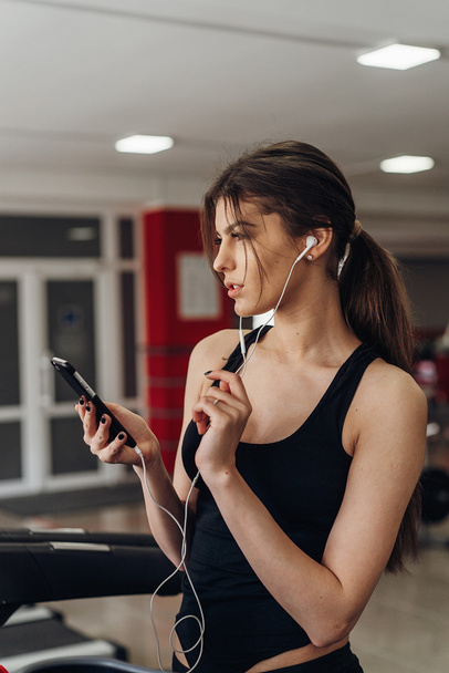 Beautiful girl with a phone in the gym - Foto, Imagen