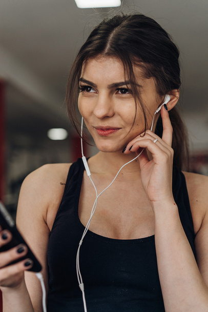 Beautiful girl with a phone in the gym - Fotó, kép