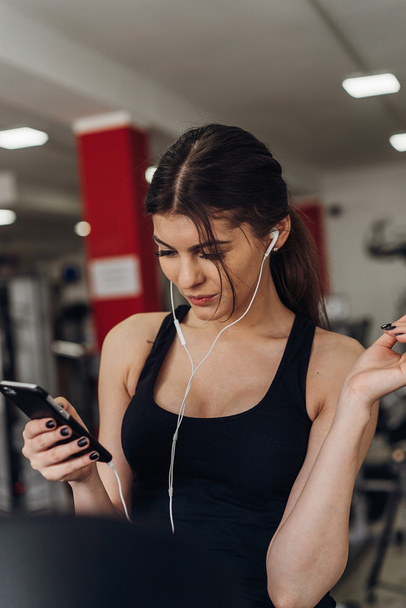 Beautiful girl with a phone in the gym - Фото, зображення
