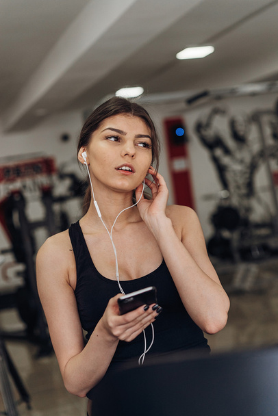 Beautiful girl with a phone in the gym - Foto, afbeelding