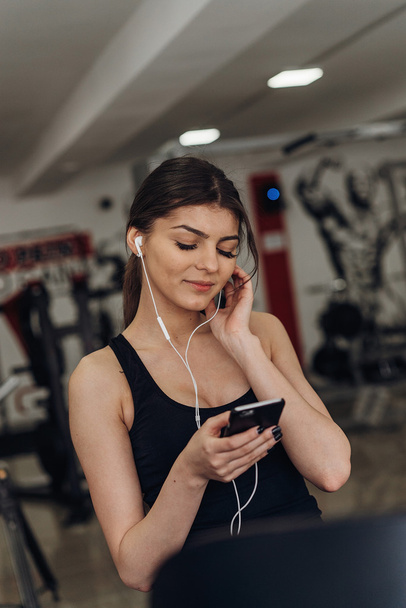 Beautiful girl with a phone in the gym - Фото, зображення