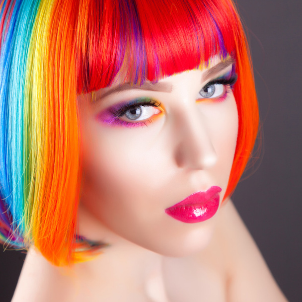 hermosa mujer vistiendo peluca colorida y mostrando uñas coloridas
  - Foto, imagen