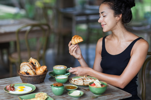 Mladá žena, snídani a v ruce drží rohlík. Ráno dobrou náladu - Fotografie, Obrázek