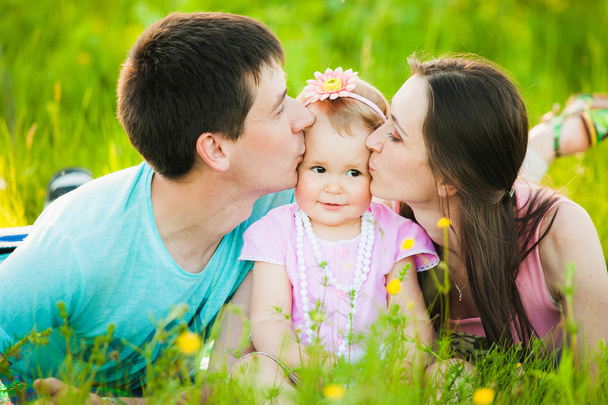 Mamma e papà baciano le guance della figlioletta. Ritratto di famiglia
. - Foto, immagini