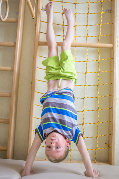 Child stands upside down in gym  - Foto, Bild