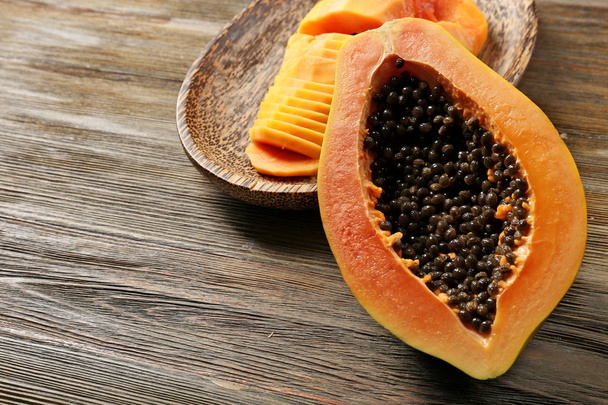 Halved papaya with slices on a wooden plate - Foto, Bild
