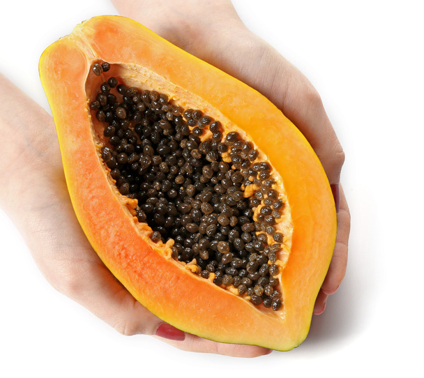 Female hands holding a halved papaya on white background - Foto, Bild