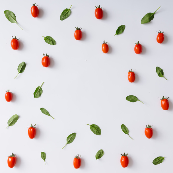 Wiśniowe pomidory i wzór liści bazylii. - Zdjęcie, obraz