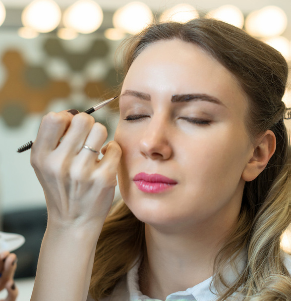 Make-up artist applying makeup on model's face. - Fotoğraf, Görsel