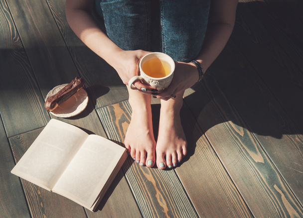 Útulné fotografie mladé ženy s šálkem čaje, sedí na podlaze  - Fotografie, Obrázek