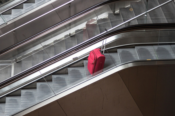 red rolling suitcase on escalator traveling alone concept - Photo, Image