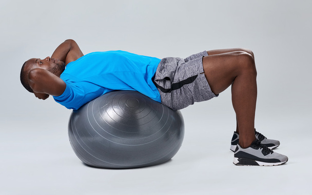 man doing core sit up exercise routine on gym ball - Fotó, kép
