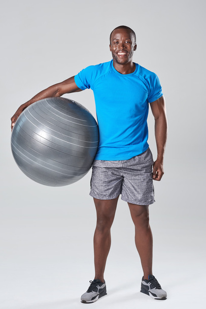 Black african man smiling holding exercise gym ball - Foto, afbeelding