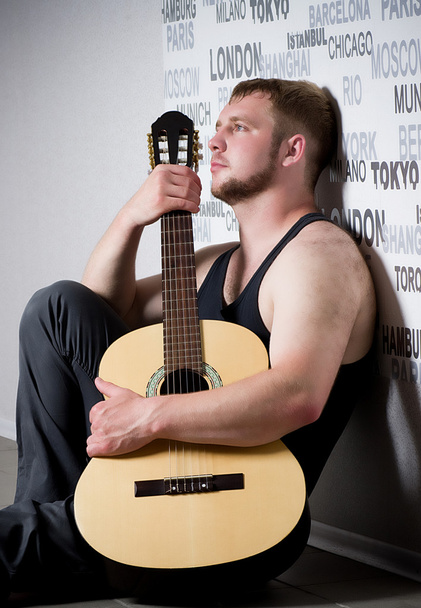 Young man with guitar on dark background - Photo, image