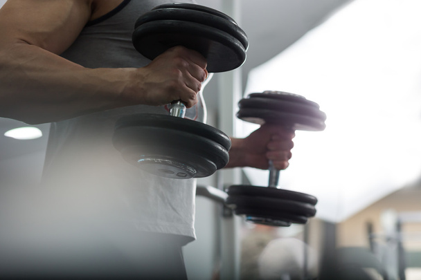 Closeup of a muscular young man lifting weights, Caucasian man - Фото, изображение