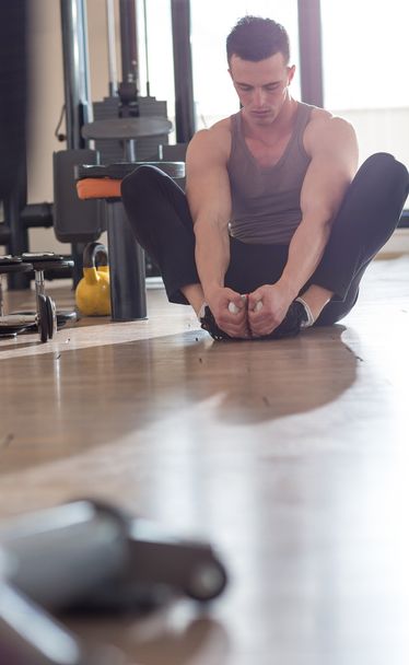 Handsome muscular man doing stretching exercise. - 写真・画像