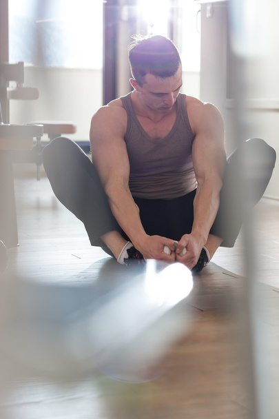 Handsome muscular man doing stretching exercise. - Foto, Imagen