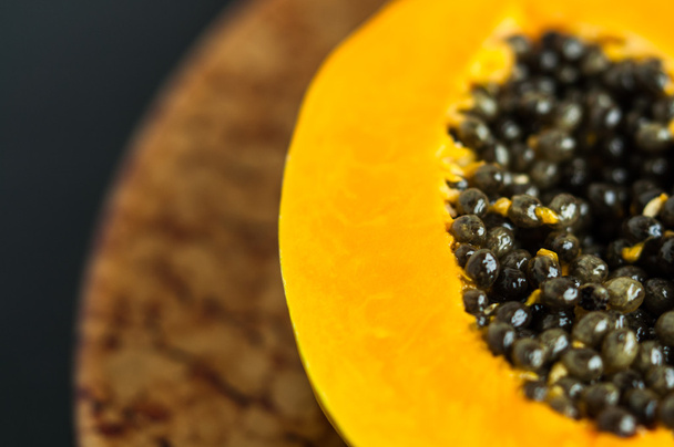 Hawaiian papaya fruit snij doormidden met zaden op een bruin bord - Foto, afbeelding