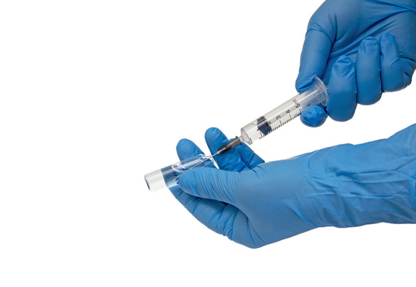 Medical gloved hand holding syringe with a bead of liquid emerging testing the function of the syringe - Φωτογραφία, εικόνα
