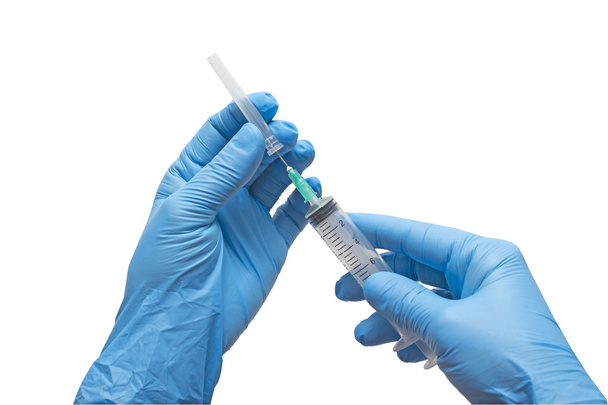 Medical gloved hand holding syringe with a bead of liquid emerging testing the function of the syringe - Foto, Bild