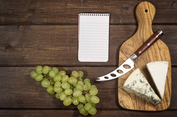 Cheese, grapes and paper notebook - Фото, изображение