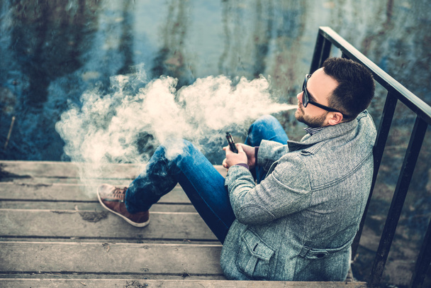 Man with beard vaping outdoor - Valokuva, kuva