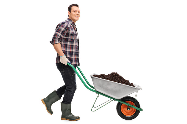 Gardener pushing a wheelbarrow full of dirt  - Fotografie, Obrázek