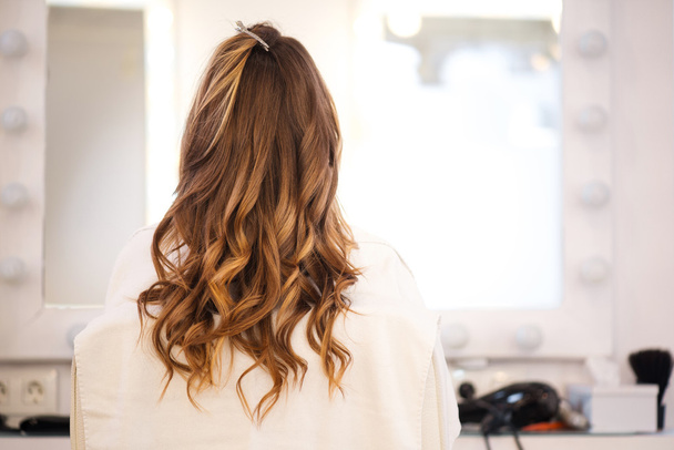 Curly woman sitting in the hairdressing salon - Photo, image