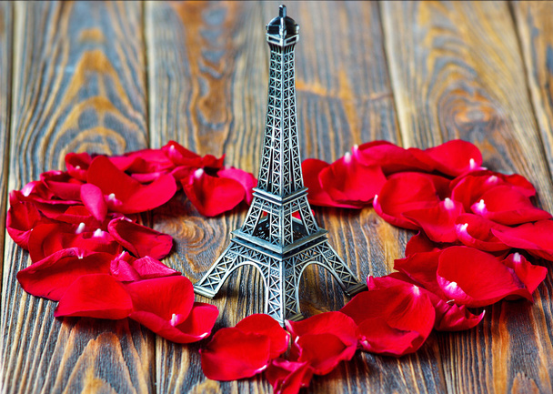 Eiffel tower statue and heart shaped red rose petals on wooden background. Travel, love concept. St Valentine's Day - Zdjęcie, obraz
