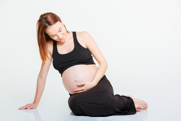 Pregnant woman sitting on the floor - Фото, изображение