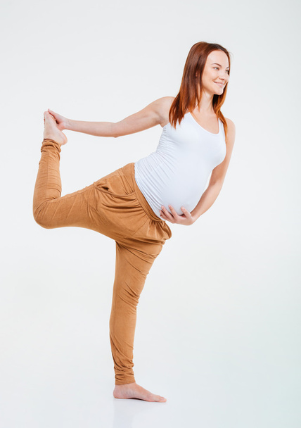 Smiling pregnant woman doing stretching exercise  - Foto, afbeelding