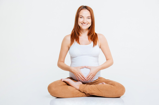 Pregnant woman showing heart gesture on her belly - Fotó, kép