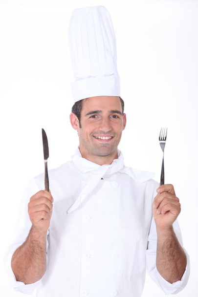Chef in whites holding a knife and fork - Фото, зображення