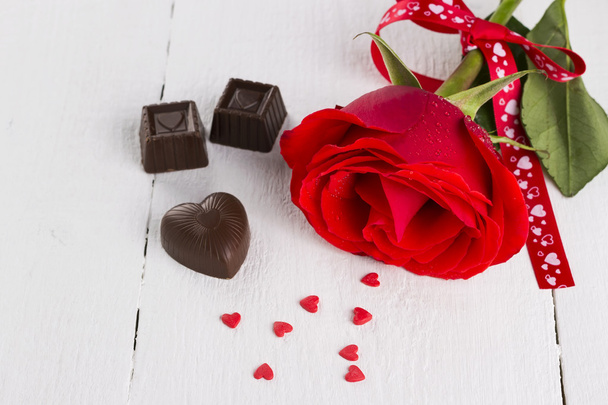 Red rose, chocolates on a white wooden background - Foto, imagen