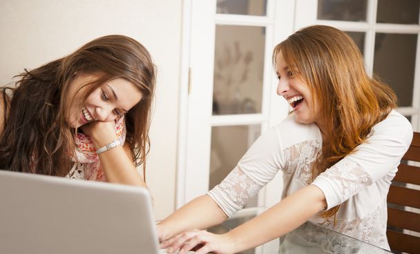 Two young women having fun in front of laptop - 写真・画像