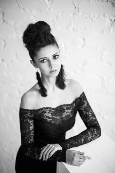 Beautiful model in black dress with evening makeup and hairdo posing - Фото, зображення