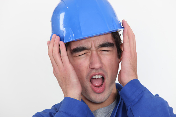 A young manual worker hearing unbearable noise. - Foto, Imagen