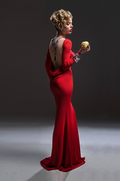  woman in red dress with apple - Fotoğraf, Görsel