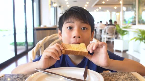 Aziatische preteens Boy eet brood zitten aan de tafel, 4k - Video