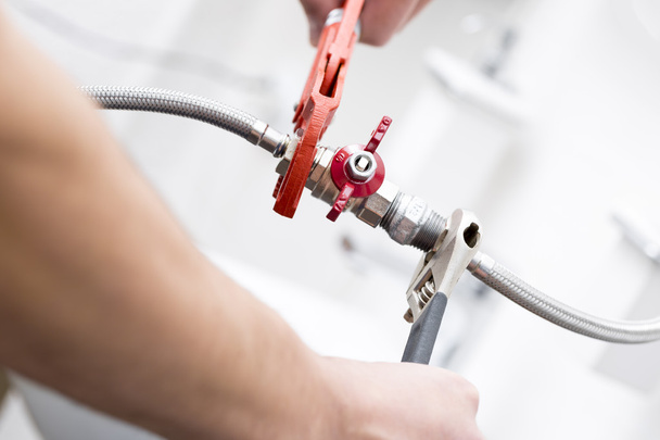 plumber screwing plumbing fittings in bathroom - Foto, Bild
